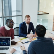 Business leaders discussing sales strategy and hiring capacity around an office meeting table