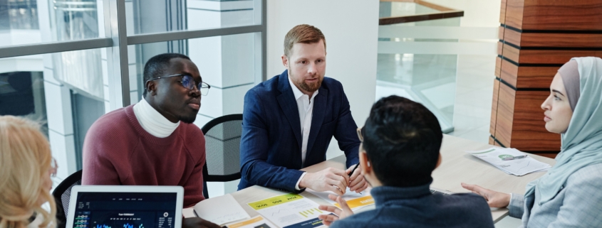 Business leaders discussing sales strategy and hiring capacity around an office meeting table