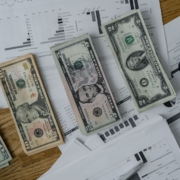 Landscape image of financial planning documents and cash on an office desk
