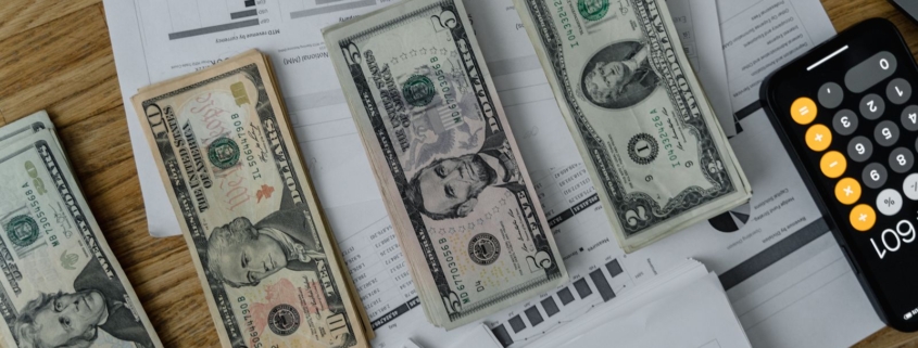 Landscape image of financial planning documents and cash on an office desk