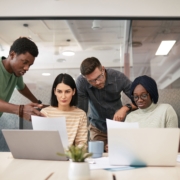 Cross-functional business team discussing planning documents and laptops during an office meeting