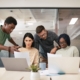 Cross-functional business team discussing planning documents and laptops during an office meeting