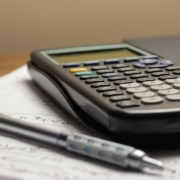 Calculator and pen on financial paperwork illustrating customer profitability and cost-to-serve analysis