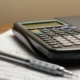 Calculator and pen on financial paperwork illustrating customer profitability and cost-to-serve analysis