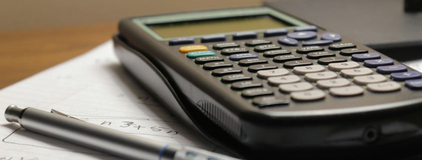 Calculator and pen on financial paperwork illustrating customer profitability and cost-to-serve analysis