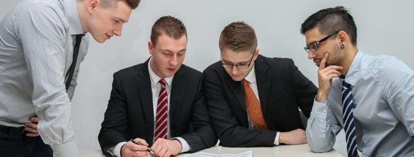 Business executives reviewing documents together at a conference table during an acquisition integration meeting