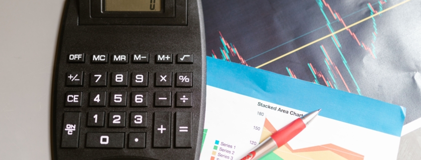 Calculator and pen beside financial charts illustrating price volume mix revenue analysis