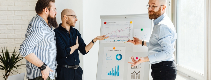 Three business professionals discussing financial charts during an executive forecast review
