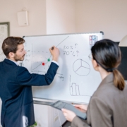 Business professionals discussing planning assumptions at a whiteboard