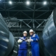 Two manufacturing workers inspecting steel coils at an industrial facility, illustrating in-house production and make-or-buy decisions