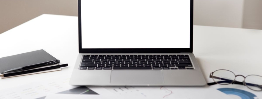 Laptop and financial paperwork on an office desk for reviewing SaaS software subscription renewal budgets