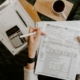 Person reviewing financial documents with a calculator and laptop