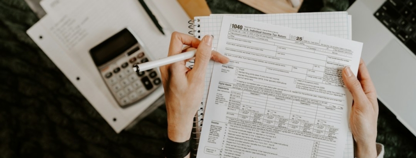 Person reviewing financial documents with a calculator and laptop